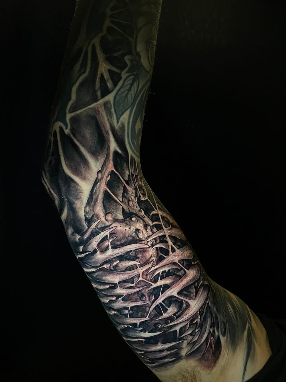 Dark-art bio-organic tattoo sleeve — skeletal, thorned forms in high-contrast black & grey
