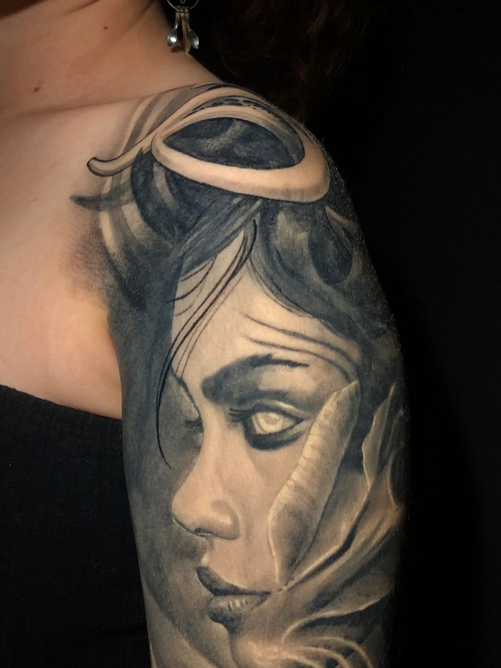 Black & grey realism tattoo — a woman's veiled face rendered in soft tonal shading across the shoulder